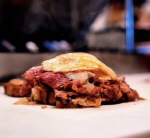 Layered meat on a reuben sandwich topped with an egg at Mythical Wich