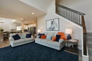 Open-concept living room with two sofas and a staircase to upper floors in Journey's Remedy home in Branson, Missouri