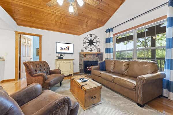 Cozy cabin living room with a stone gas fireplace and vaulted wood ceiling at a Branson Christmas lights getaway