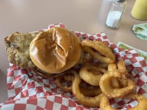 Onion rings and a breaded Pork Tenderloin Sandwich, the two must-try dishes at White Lightning Restaurant in Lampe