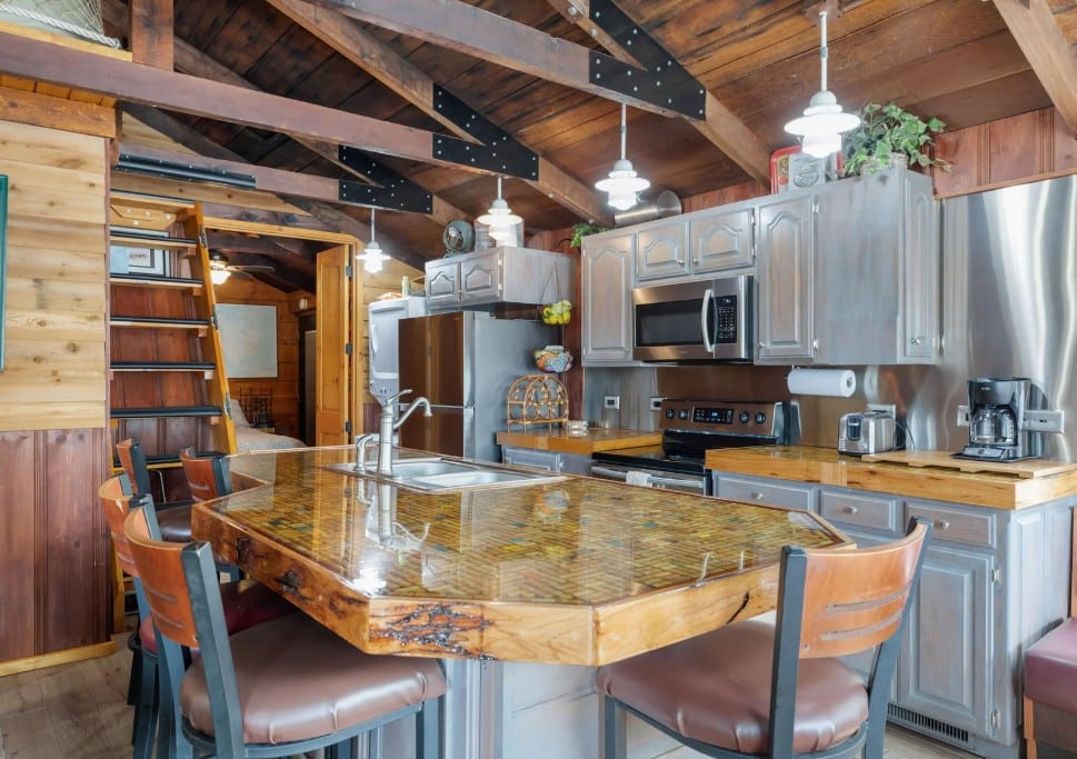 Rustic cabin kitchen with exposed wood beams, a loft ladder, and a custom bar-height island at a Branson lake house rental