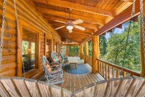 Covered wooden porch at Lazy K Cabin with rocking chairs and views of the surrounding woods.