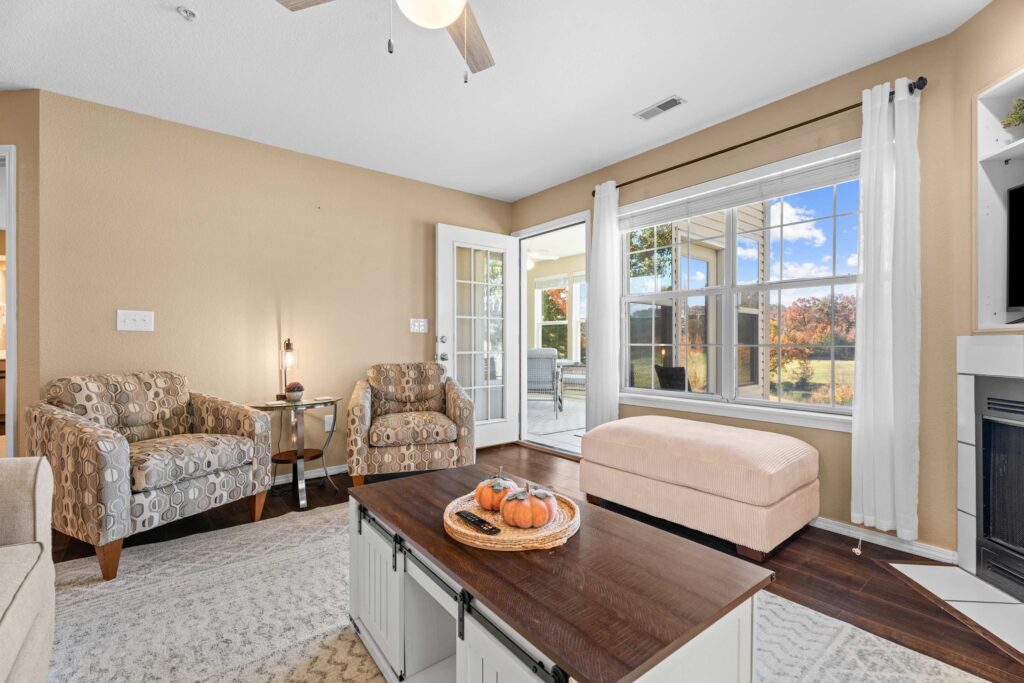 Living room with French doors to a sunroom and a window view of the golf course at Backyard Breeze Condo in Branson